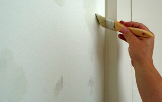 painter fixing peeling paint on walls